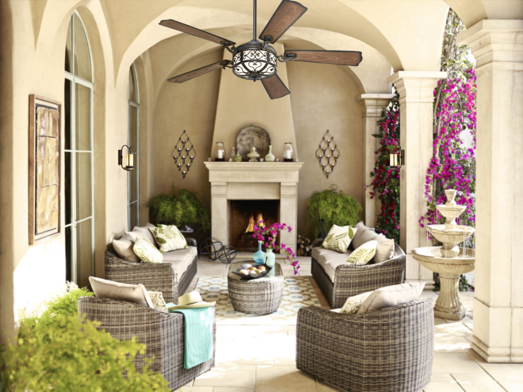 An outdoor ceiling fan in a covered outdoor area with furniture and a fountain. 