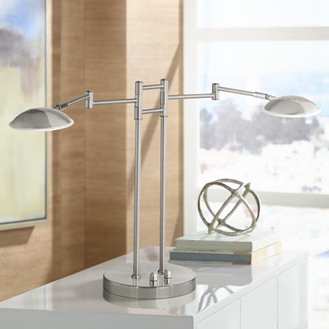 A swing arm LED desk lamp on a white table. 